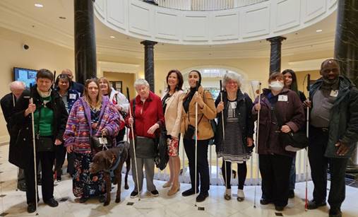 NFBMD members stand with sponsor Delegate Michele Guyton at House Accessible Prescription Labels bill hearing