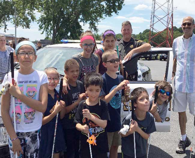 shows a group of BELL students posing in front of a sheriff’s car