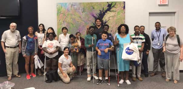 shows a group of BELL students, teachers and volunteers posing in front of a large map.