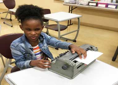 shows a girl re-reading what she has Brailled on her Brailler.